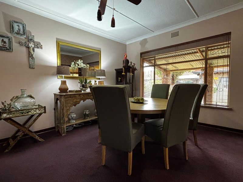 A dining room featuring carpeted flooring, a ceiling fan, and a large window providing natural light and views of the outdoor patio area.