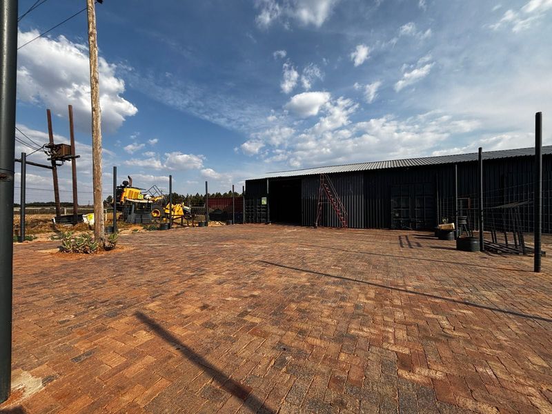 Spacious industrial property featuring a large paved yard and a corrugated metal warehouse structure.