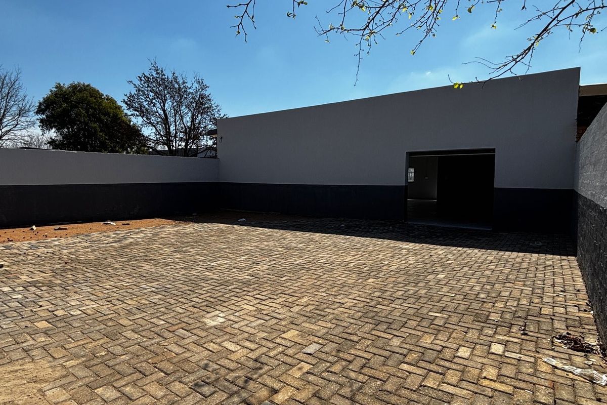 A clean, paved rear courtyard area featuring high boundary walls and a direct access point to the building interior.