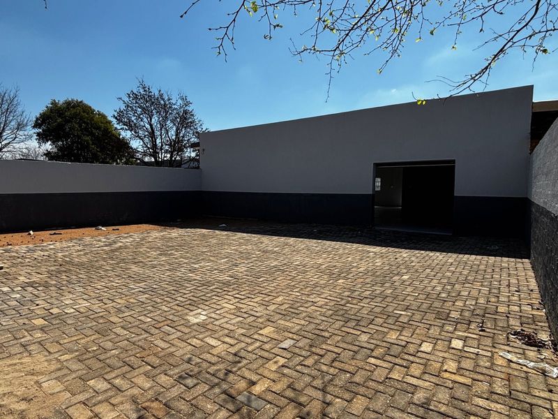 A clean, paved rear courtyard area featuring high boundary walls and a direct access point to the building interior.