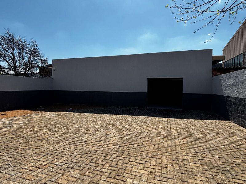 A paved rear courtyard area featuring a secure roller shutter door access point and perimeter boundary walls.