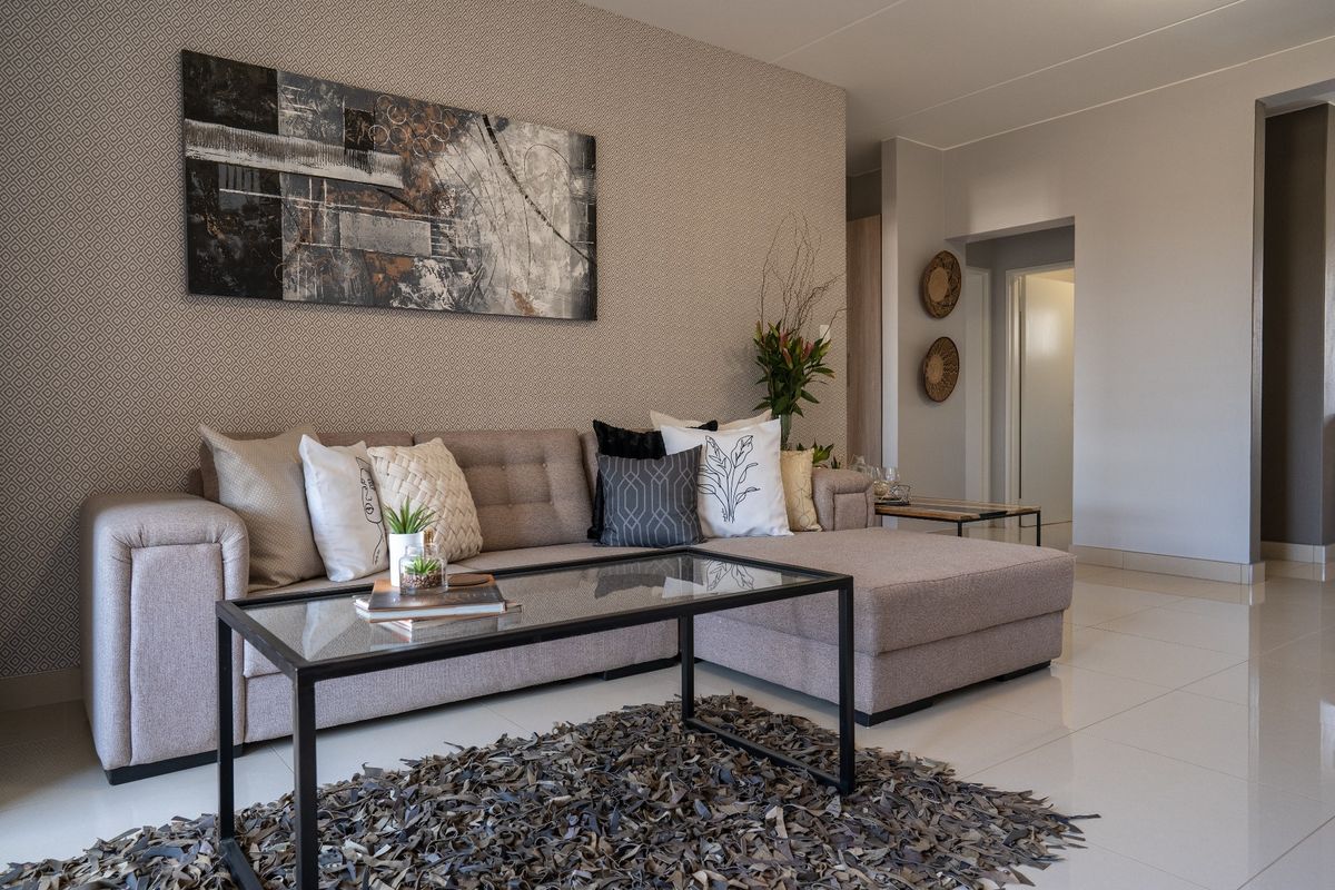 A well-maintained living room featuring neutral tiled flooring and a decorative patterned feature wall, creating a modern and inviting atmosphere.