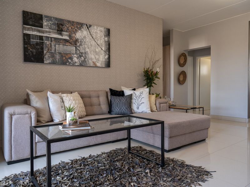A well-maintained living room featuring neutral tiled flooring and a decorative patterned feature wall, creating a modern and inviting atmosphere.