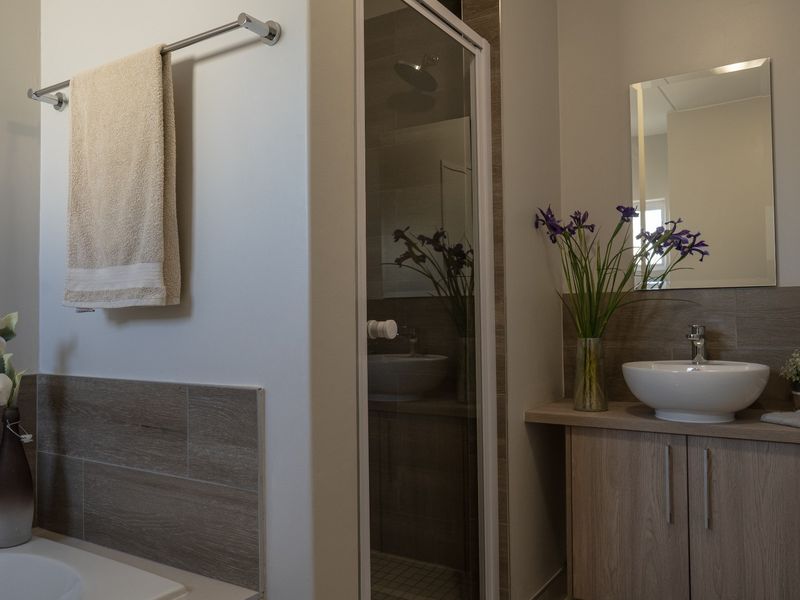 Modern bathroom featuring a vanity cabinet with a vessel sink, wall mirror, and a separate shower enclosure with tiled finishes.