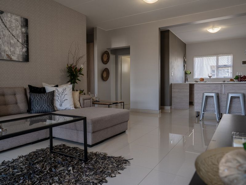 Modern open-plan living area featuring polished porcelain tiles, a functional kitchen island with breakfast bar, and contemporary finishes throughout the connected space.