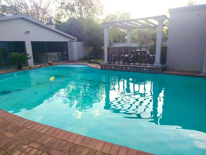 Outdoor pool area featuring a swimming pool with a raised pergola structure and brick paved surround, ideal for outdoor relaxation and entertainment.