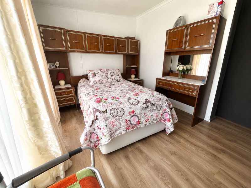 A bedroom featuring built-in wooden cabinetry and laminate flooring, offering functional storage space within a neutral interior setting.