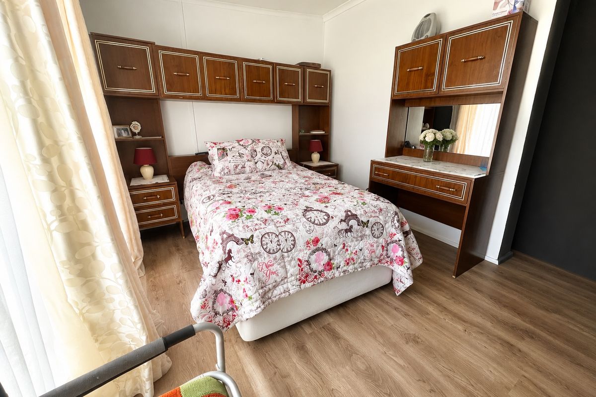 A bedroom featuring built-in wooden cabinetry and laminate flooring, offering functional storage space within a neutral interior setting.