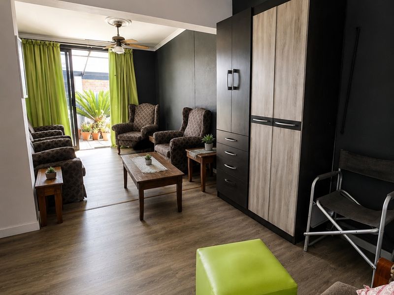 A living room featuring laminate flooring, a ceiling fan, and a sliding glass door providing access to an outdoor area.