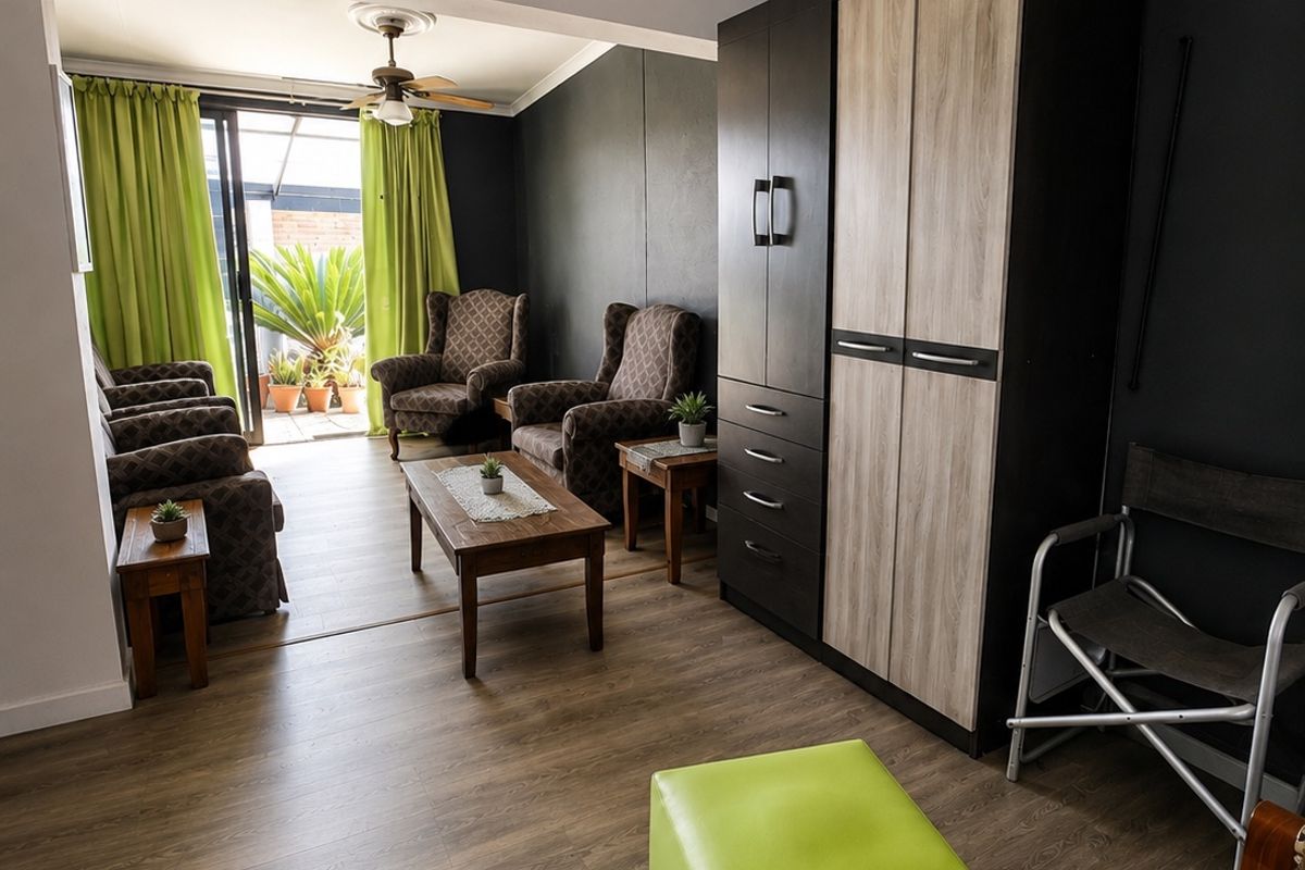 A living room featuring laminate flooring, a ceiling fan, and a sliding glass door providing access to an outdoor area.