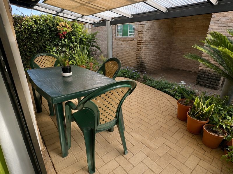 A covered outdoor patio area featuring paved flooring and brick wall construction, providing a functional space for outdoor relaxation.