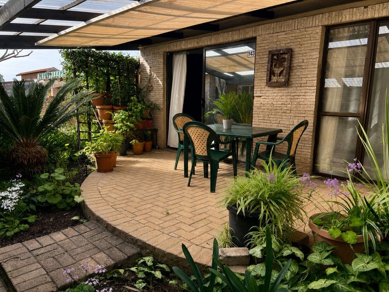 A covered outdoor patio area featuring brick paving and direct access to the interior through a sliding glass door.