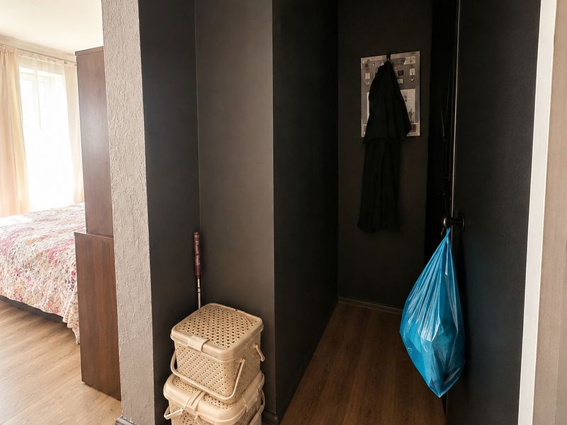 A clean hallway featuring dark painted walls, laminate flooring, and recessed lighting, providing access to the adjacent bedroom.