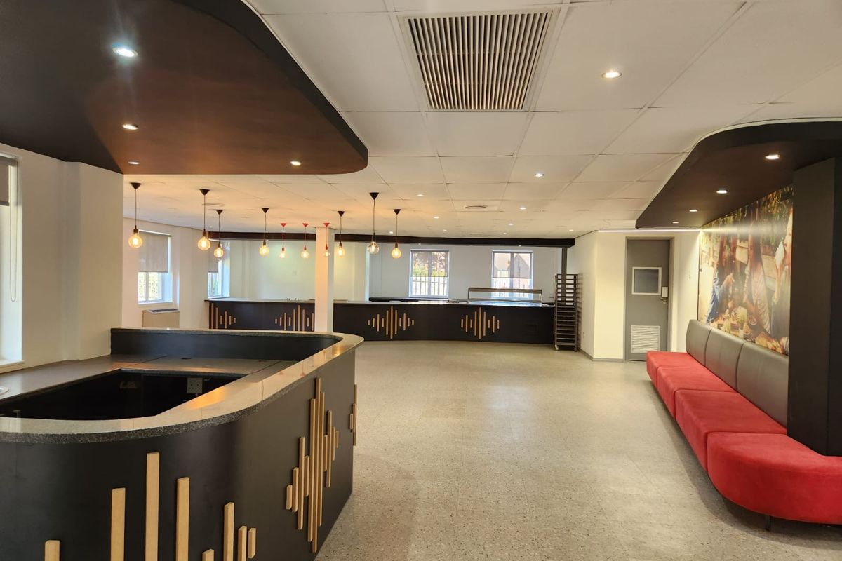 Spacious open-plan commercial area featuring a built-in service counter, modern pendant lighting, terrazzo flooring, and integrated bench seating.