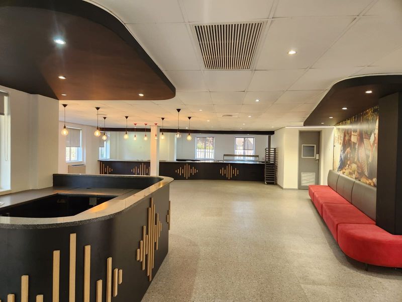 Spacious open-plan commercial area featuring a built-in service counter, modern pendant lighting, terrazzo flooring, and integrated bench seating.