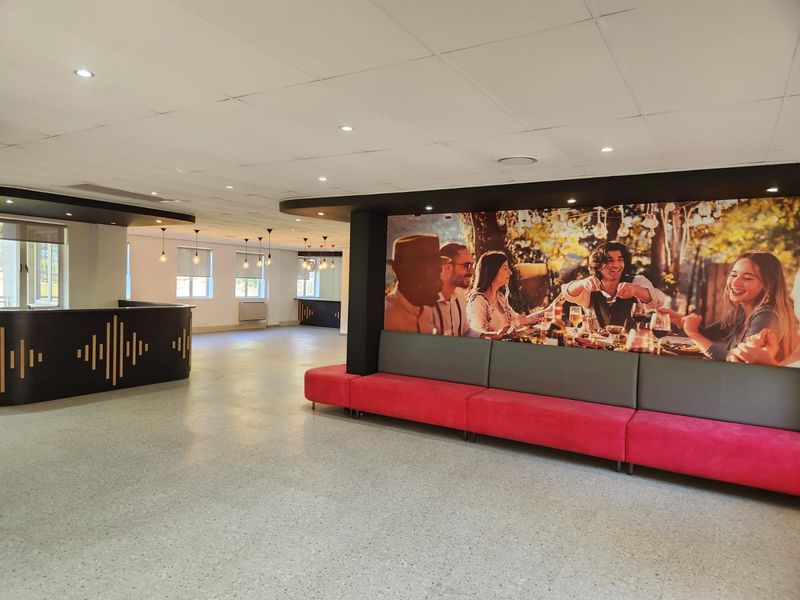 Spacious open-plan commercial area featuring terrazzo flooring, a suspended ceiling with recessed lighting, and a built-in reception counter with integrated bench seating.