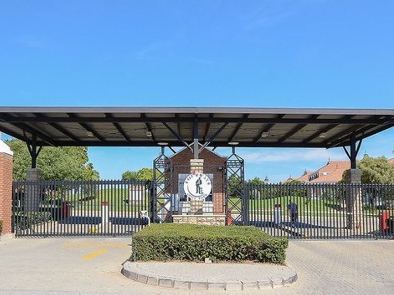 A secure commercial property entrance featuring a large metal canopy, brick gatehouse, and automated security gates.