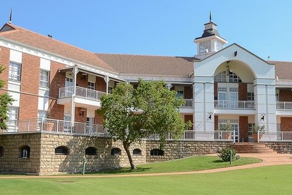 A well-maintained commercial building featuring a classic brick and stone facade, multiple balconies with metal railings, and a prominent central cupola.