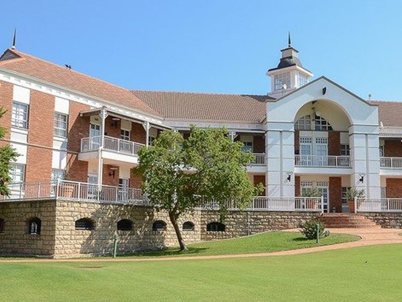 A well-maintained commercial building featuring a classic brick and stone facade, multiple balconies with metal railings, and a prominent central cupola.