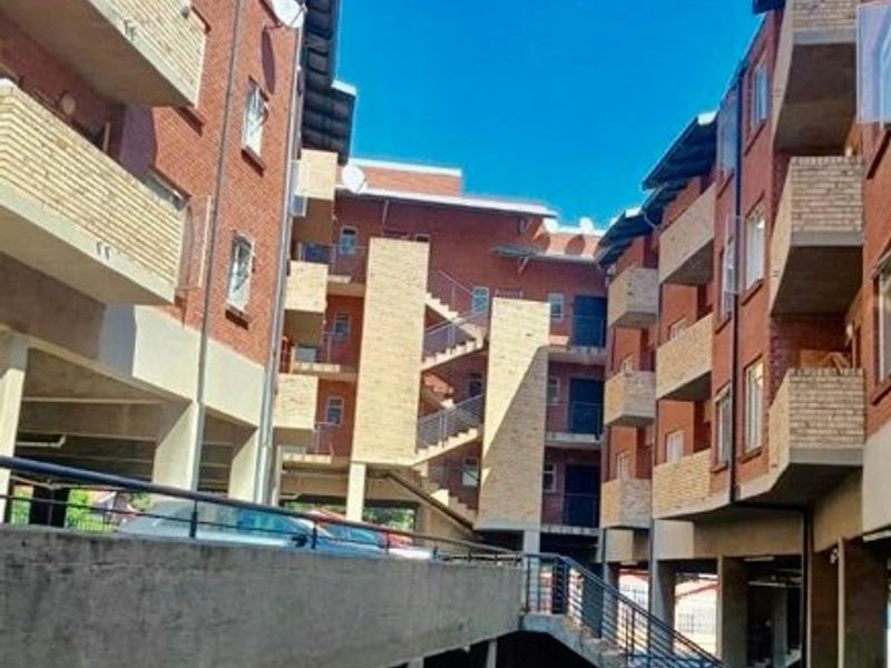 Exterior view of a multi-story apartment complex featuring exposed brick facades, concrete staircases, and private balconies.