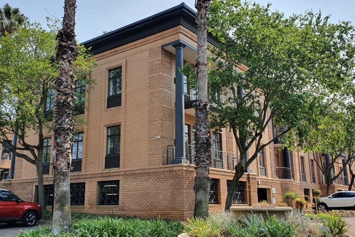 A well-maintained multi-story commercial building featuring a classic face brick facade, black structural columns, and integrated balcony railings.