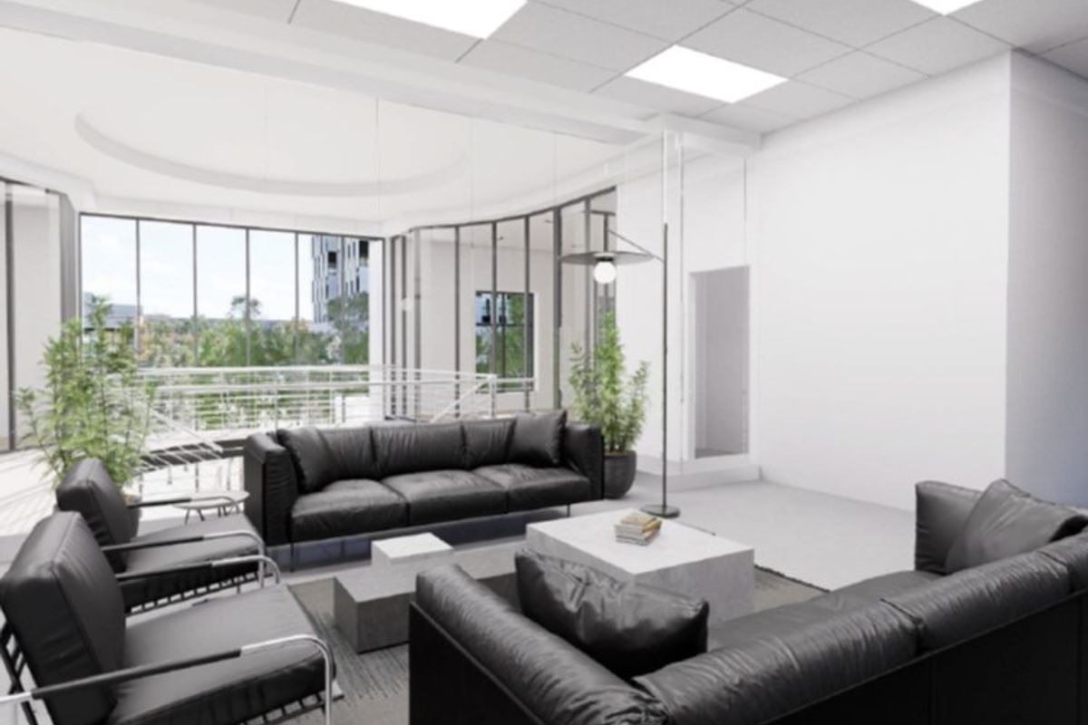 A modern, open-plan commercial lounge area featuring high ceilings, recessed lighting, and expansive floor-to-ceiling windows with a view.