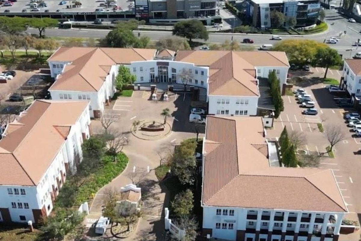 Aerial view of a commercial office park complex featuring multiple buildings, a central courtyard, and ample paved parking facilities.