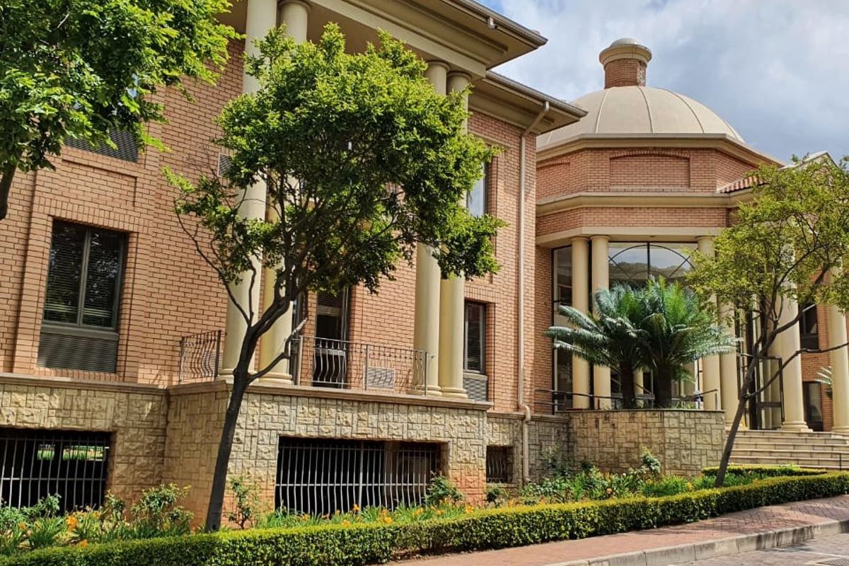 A well-maintained commercial building facade featuring classic brickwork, stone base detailing, prominent columns, and a distinctive dome architectural element.