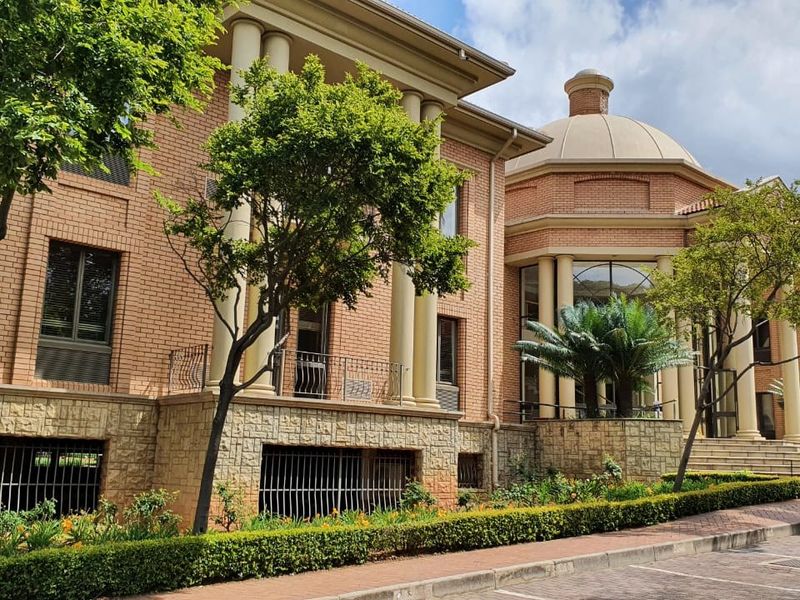 A well-maintained commercial building facade featuring classic brickwork, stone base detailing, prominent columns, and a distinctive dome architectural element.