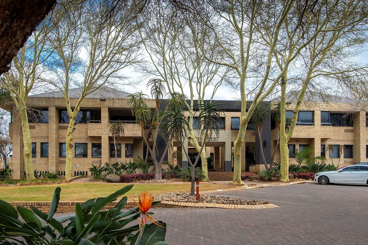 A well-maintained commercial property featuring a brick facade, paved driveway, and established garden landscaping at the front entrance.