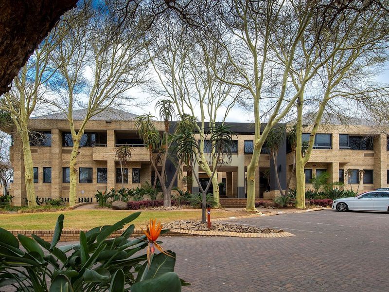 A well-maintained commercial property featuring a brick facade, paved driveway, and established garden landscaping at the front entrance.