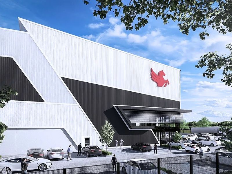 Modern industrial facility featuring a striking geometric facade with metal cladding, integrated canopy, and ample on-site parking.