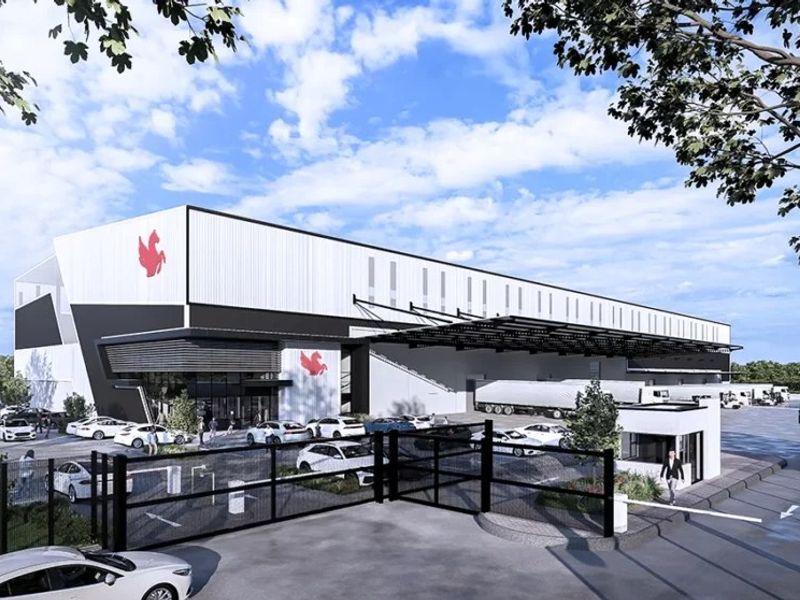 Modern industrial warehouse facility featuring large loading docks, secure gated access, and ample parking space for logistics operations.