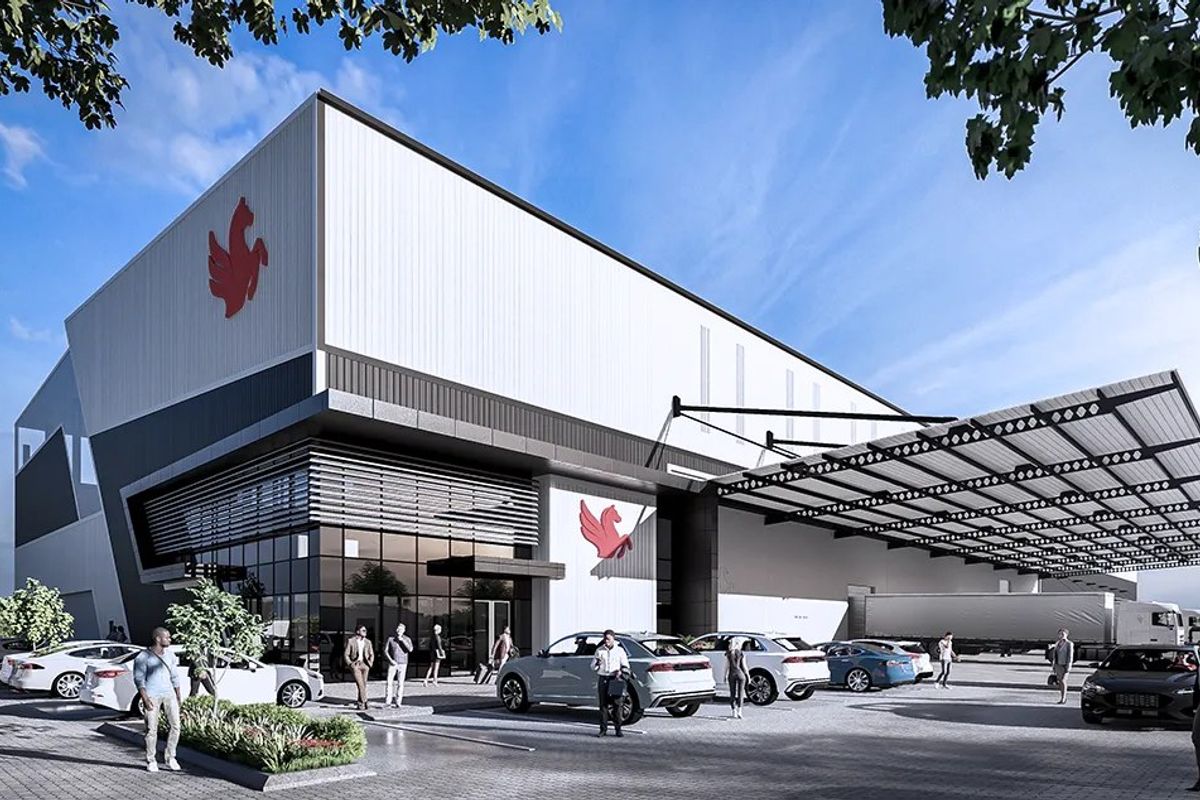 Modern industrial facility featuring a large warehouse structure with metal cladding, glass facade, and an expansive covered loading bay area.