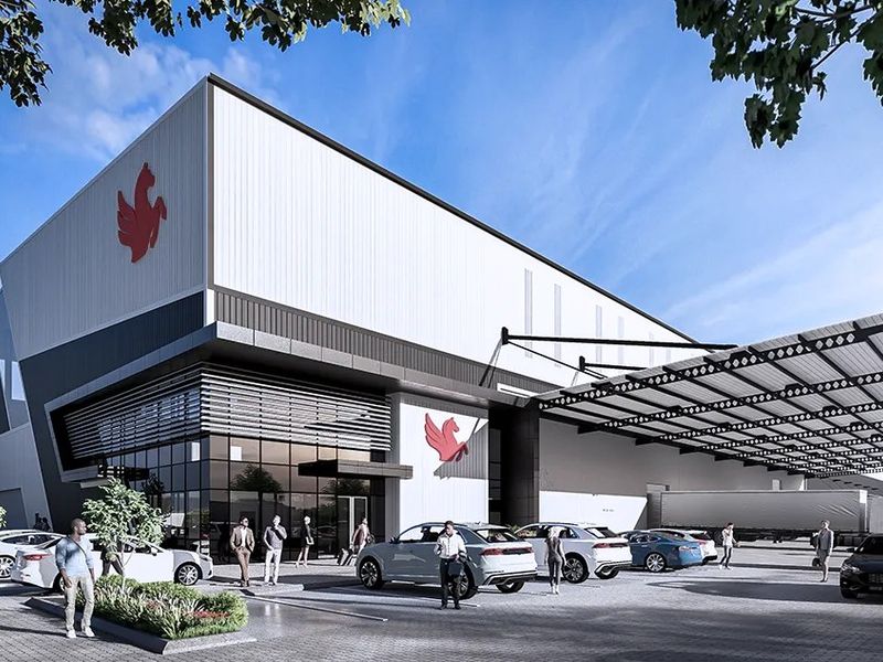 Modern industrial facility featuring a large warehouse structure with metal cladding, glass facade, and an expansive covered loading bay area.