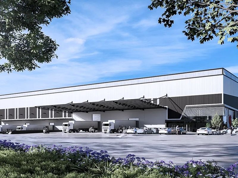 Modern industrial warehouse facility featuring a large loading canopy, expansive asphalt yard, and contemporary metal cladding exterior.