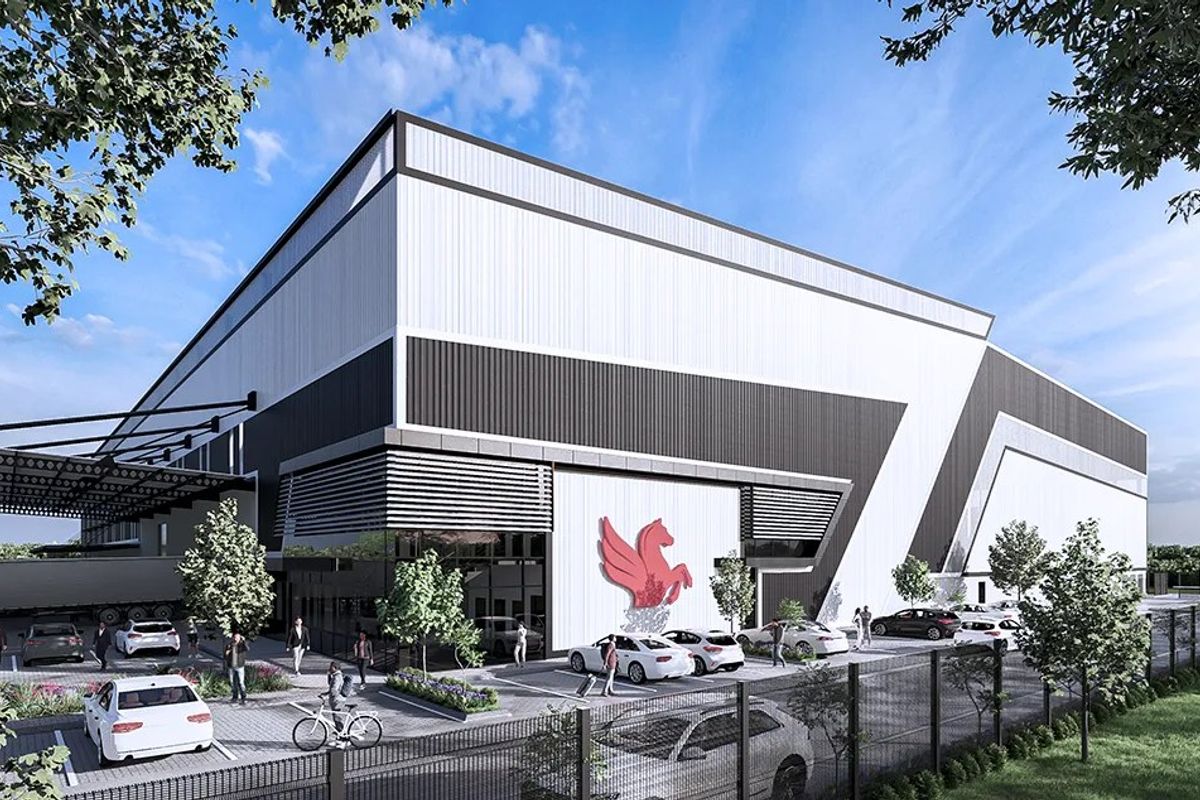 Modern industrial facility featuring large-scale metal cladding, a prominent loading bay canopy, and dedicated paved parking area within a secure fenced perimeter.