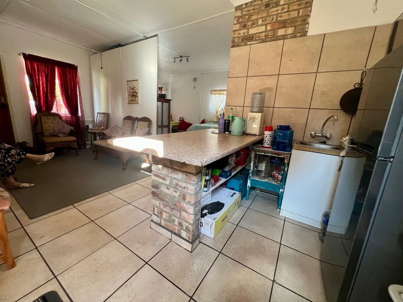 Open plan living area featuring a brick breakfast bar, tiled flooring, and a compact kitchenette area with sink and tiled splashback.