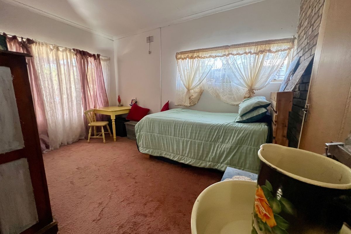 A bedroom featuring a brick fireplace and carpet flooring, offering a functional space with potential for modernization and cosmetic updates.