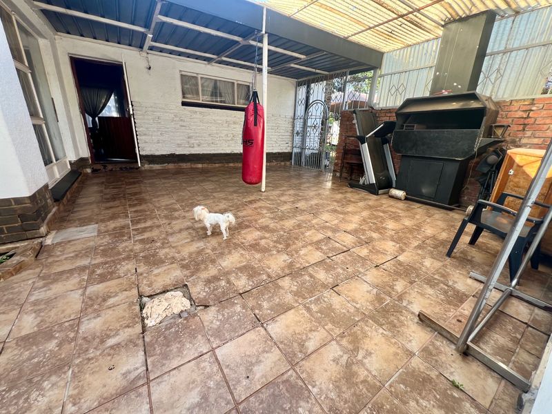 Covered outdoor patio area featuring a built-in braai, tiled flooring, and direct access to the home interior.