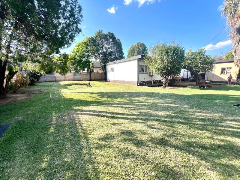 A spacious rear garden featuring a well-maintained lawn, perimeter fencing, and a view of the rear building elevation.