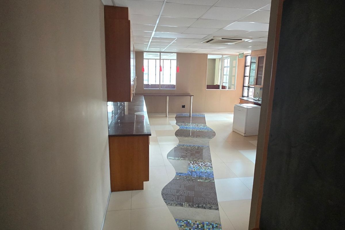 Spacious commercial kitchen area featuring built-in cabinetry, granite countertops, and a unique mosaic floor inlay, offering a functional layout for office or business use.