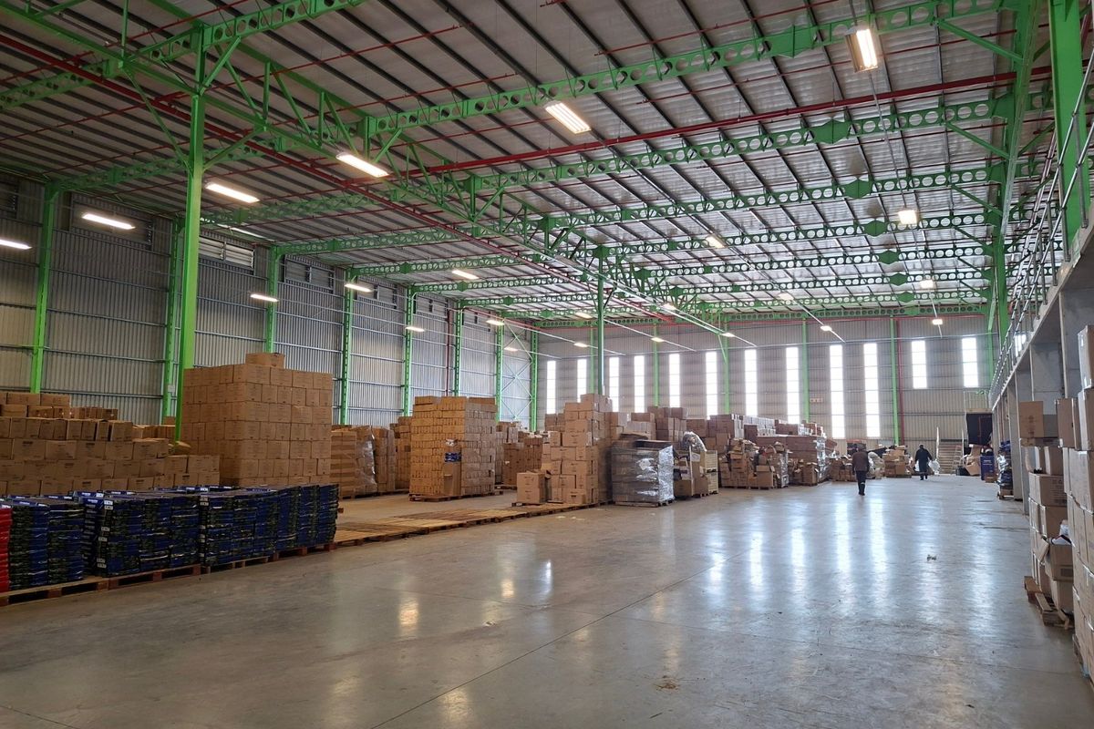 Spacious industrial warehouse featuring high ceilings with exposed steel trusses, polished concrete floors, and ample natural light through high-level windows.
