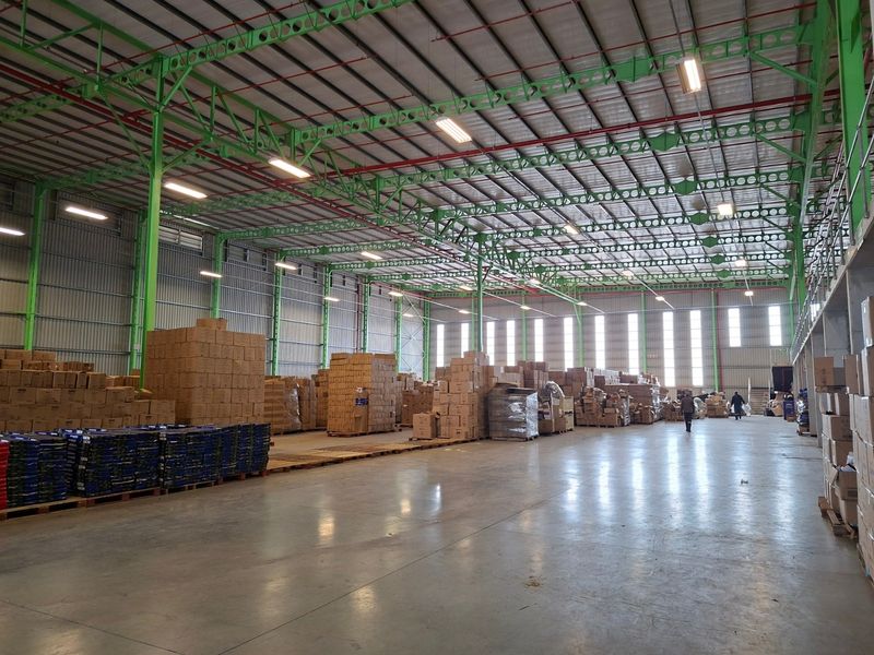 Spacious industrial warehouse featuring high ceilings with exposed steel trusses, polished concrete floors, and ample natural light through high-level windows.