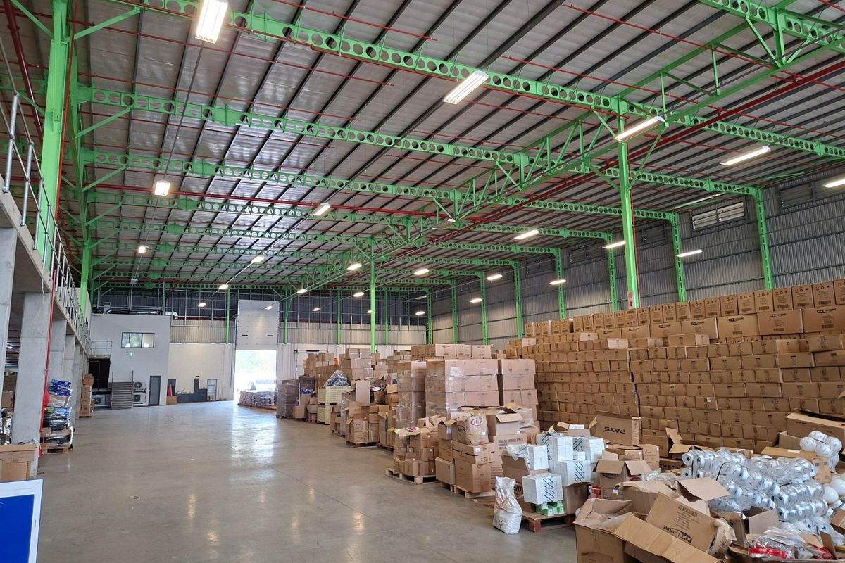 Spacious industrial warehouse featuring high ceilings with exposed steel trusses, concrete flooring, and a mezzanine level, suitable for storage or manufacturing operations.