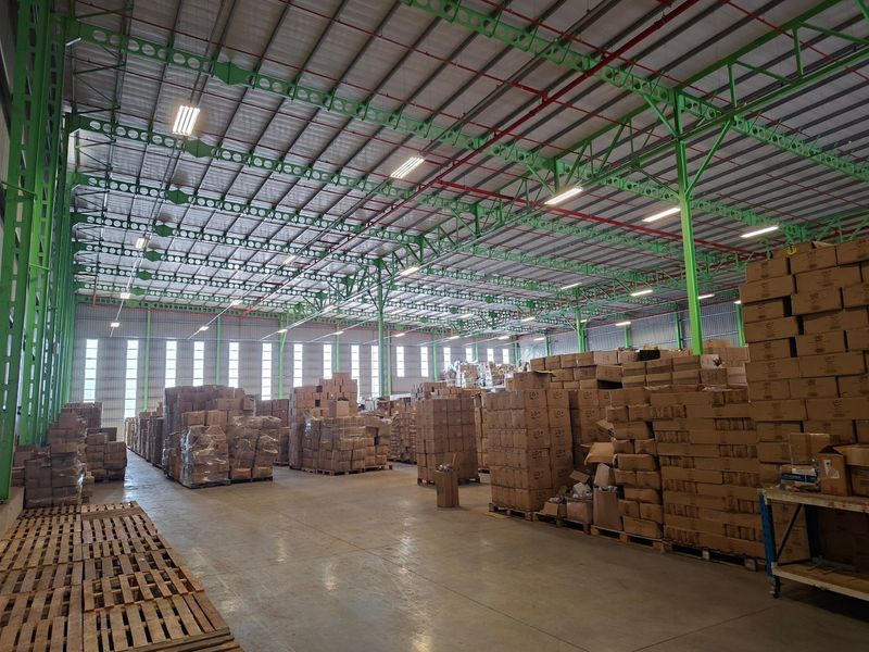 Spacious industrial warehouse featuring high-clearance steel truss roofing, integrated sprinkler system, polished concrete flooring, and ample natural light through high-level windows.