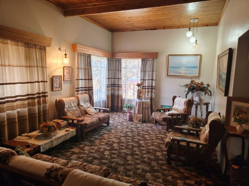 A traditional living room featuring a warm timber tongue and groove ceiling with exposed beams and classic window pelmets.
