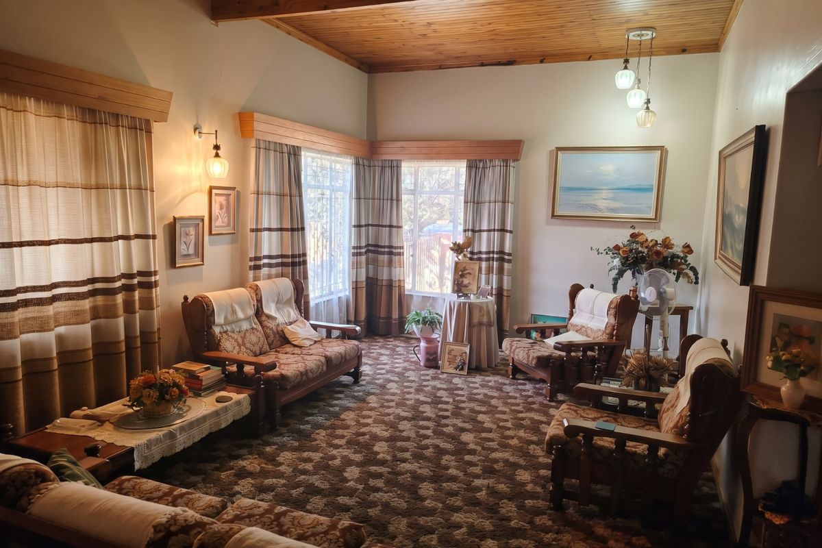 A traditional living room featuring a warm timber tongue and groove ceiling with exposed beams and classic window pelmets.