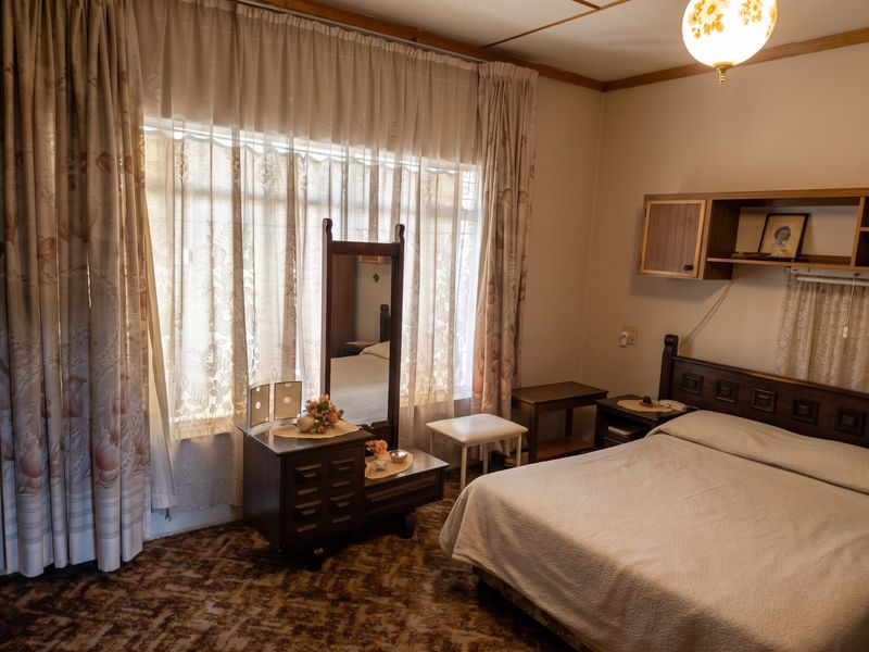 A bedroom featuring patterned carpet flooring and built-in wall shelving, offering a functional space with natural light from the large window.