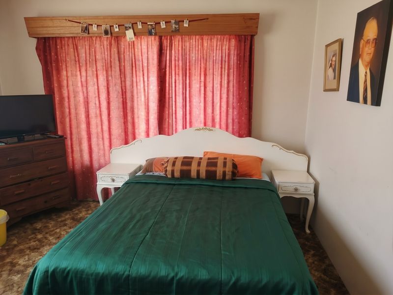 A bedroom featuring a wooden curtain pelmet and carpeted flooring, offering a dated aesthetic that could be updated with modern finishes.